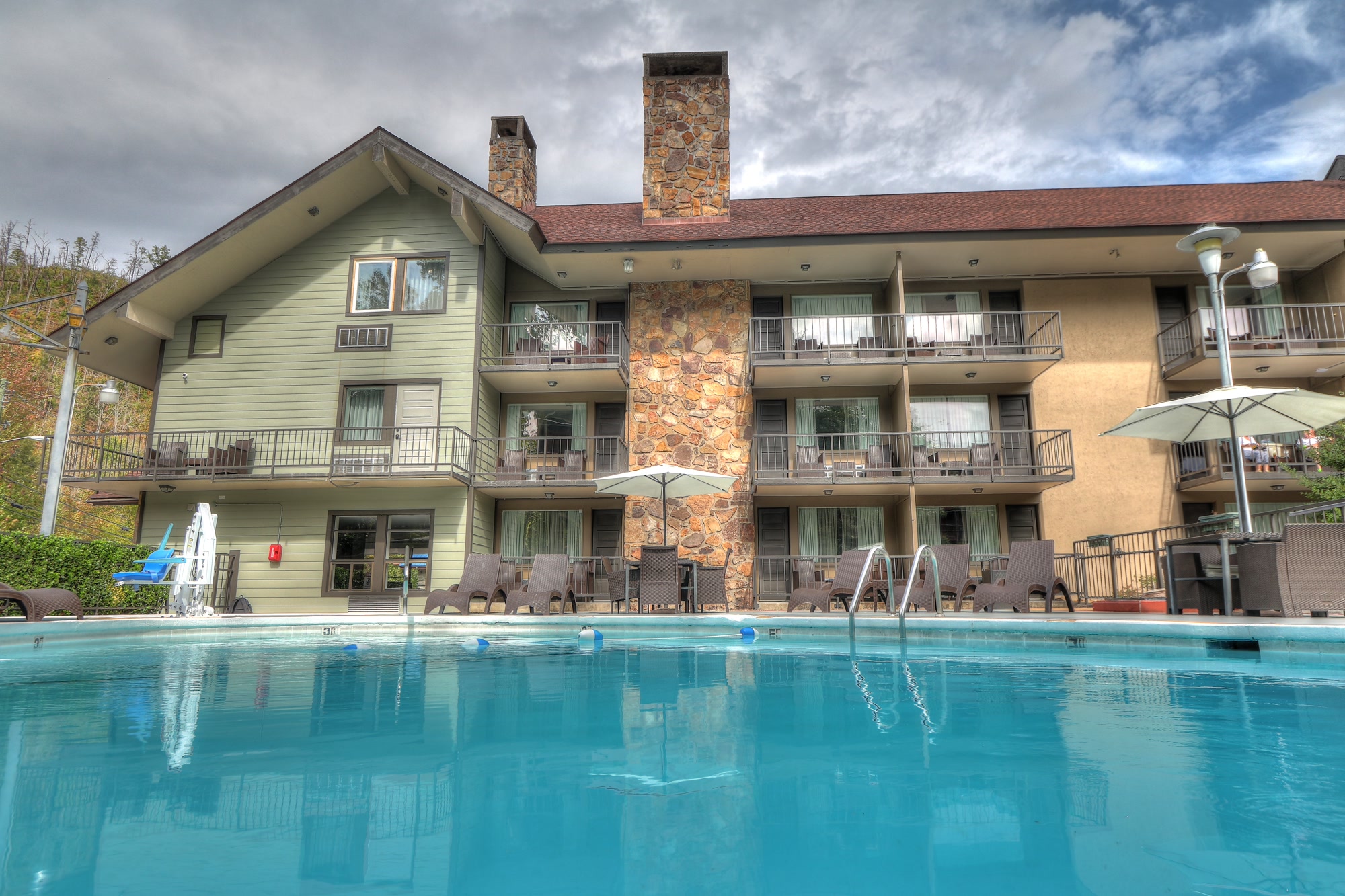 A hotel building with balconies and a pool in front of it.